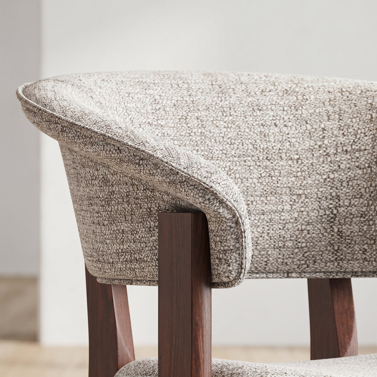 Close-up of the Halo Luxe dining chair’s curved upholstered backrest, piped edge and dark solid oak frame